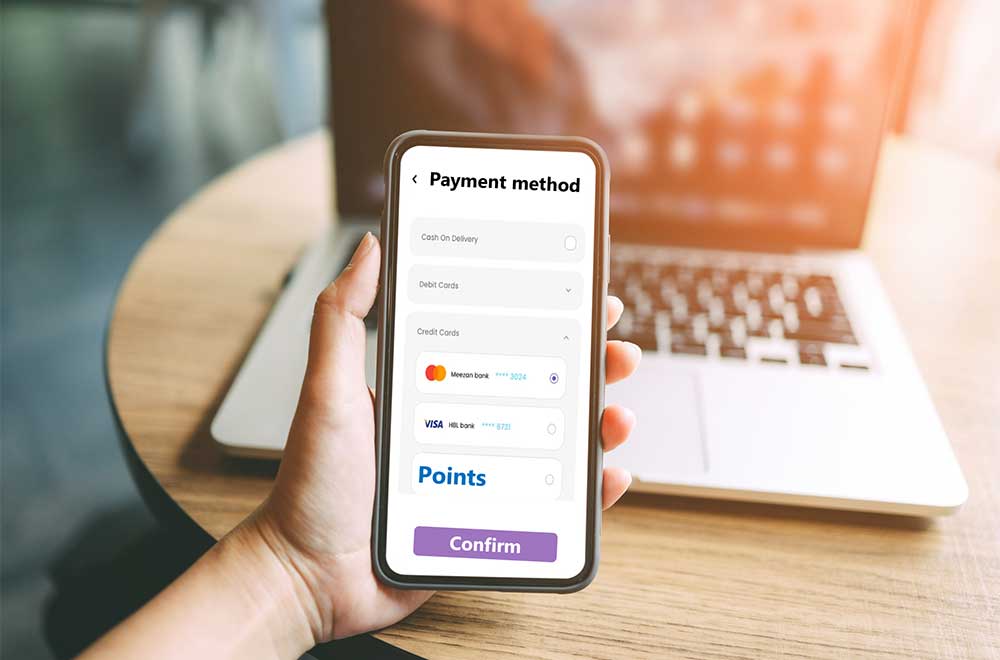 Hand holding a smartphone showcasing different payment methods.