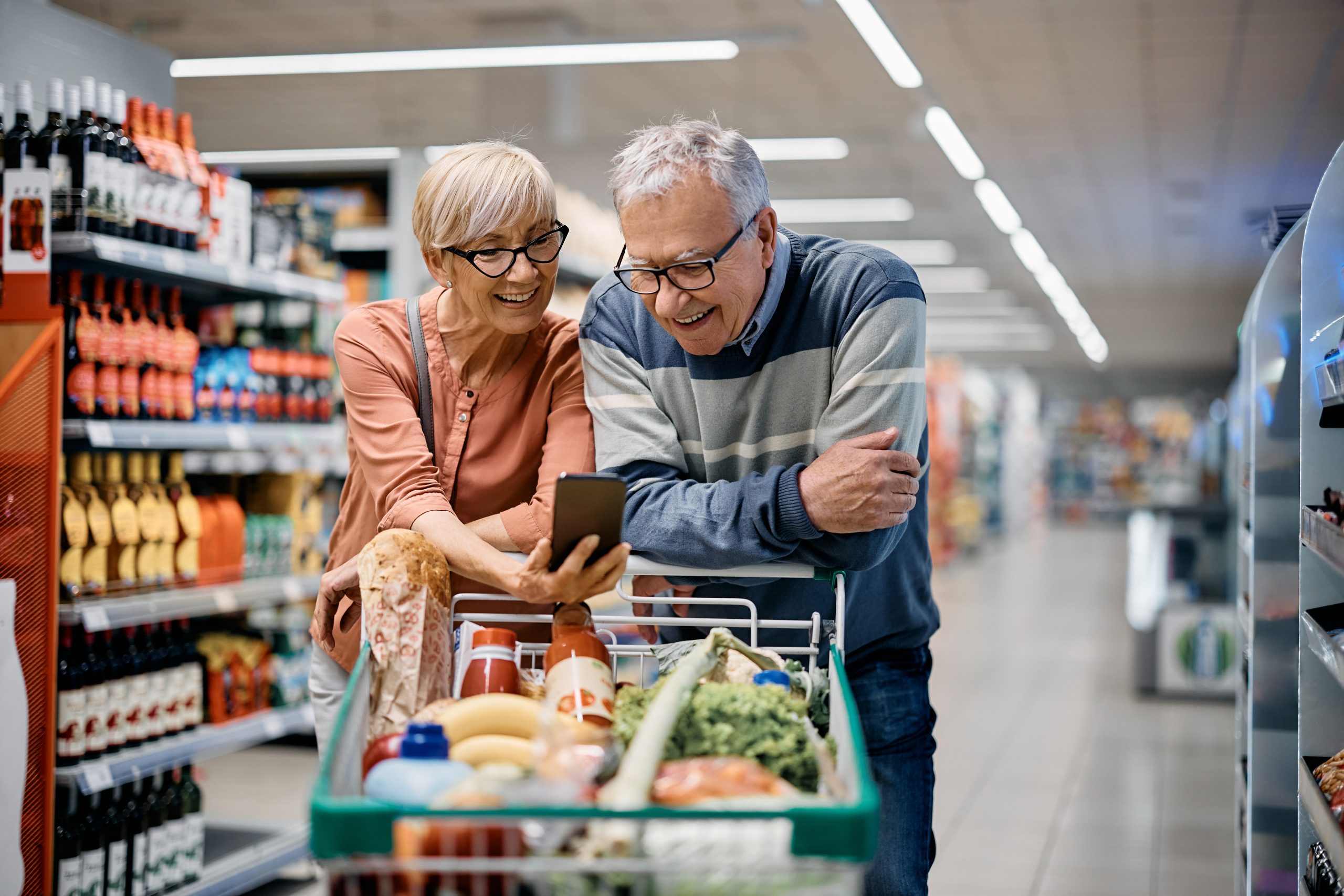 An elderly couple engaging in their loyalty program on their phone.