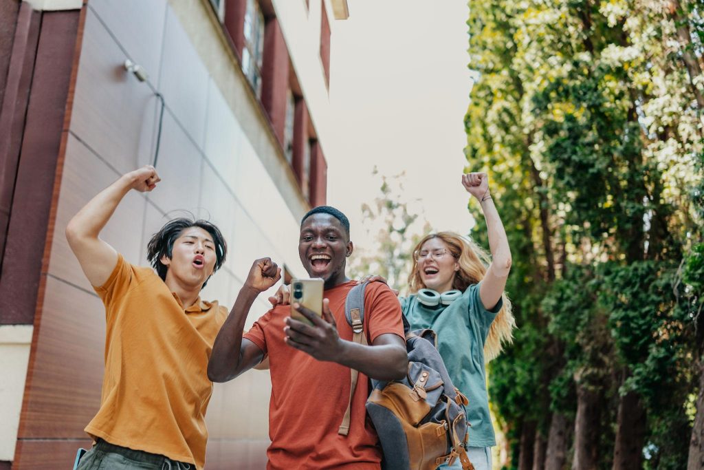 Designing Group Driven Loyalty Programs featuring three happy people jumping, looking at a phone together.