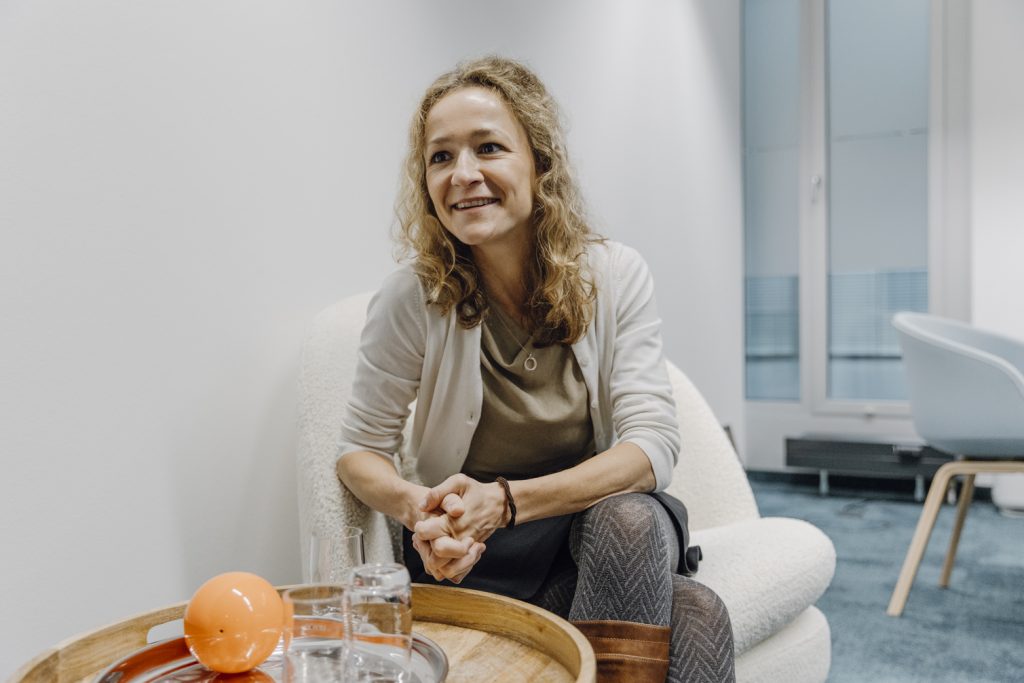 Smiling woman seated in a modern office lounge during a conversation.